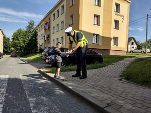 Policjant zakładający dziecku odblask na rękę.