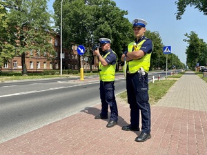 Policjanci stojący przy ulicy podczas kontroli rejonu.