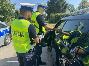 Dwóch umundurowanych policjantów podczas kontroli trzeźwości kierowcy.