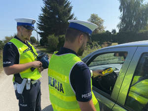 Dwóch umundurowanych policjantów podczas kontroli trzeźwości kierowcy.