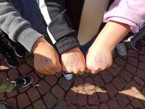 Dłonie dzieci gdzie odbite są pieczątki z napisem policja i misiem policjantem.