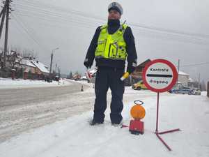 Policjant stojący przy znaku kontrola drogowa.