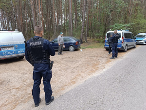 Policjanci podczas rozmowy z grzybiarzami w lesie.