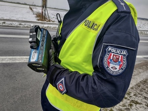 Policjant podczas mierzenia prędkości kierujących samochodami.