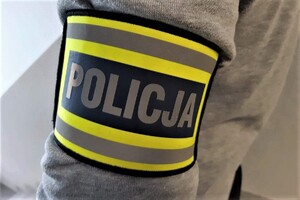 Opaska  z napisem "policja" na przedramieniu nieumundurowanego policjanta.